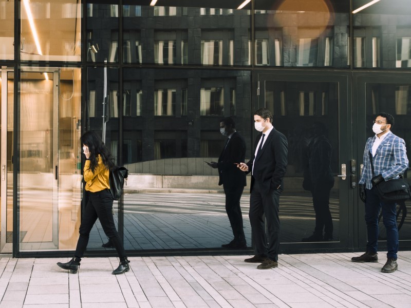 people standing in a queue, maintaining social distancing while wearing a mask at entry