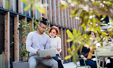 Two persons using laptop outside the building