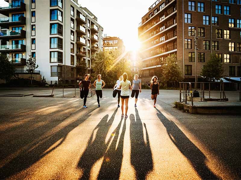 A fitness instructor talking to her class outdoors in the city.