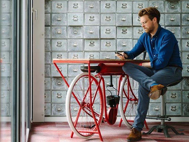 Man sitting near to some innovative bicycle and working on phone