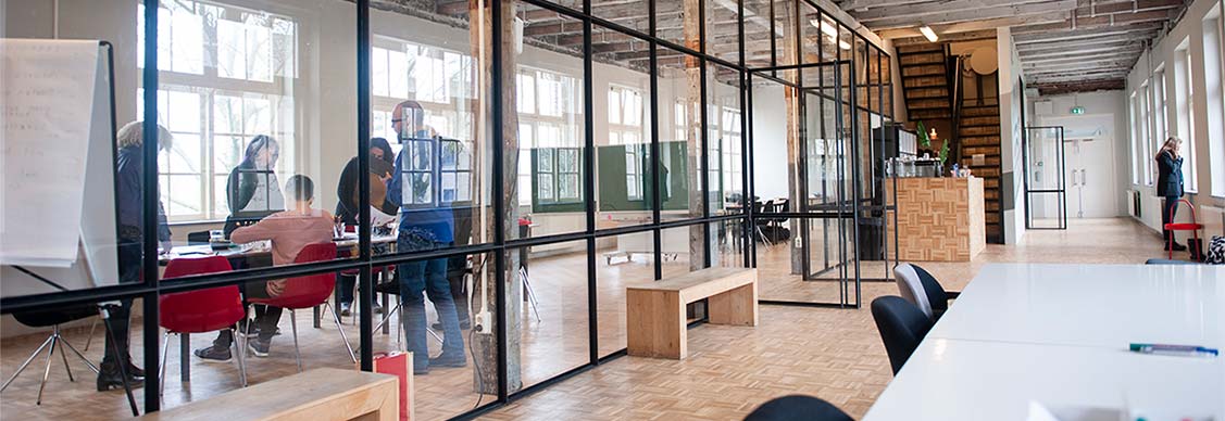 Beautiful modern office space in an old building. A team is working and a woman is making a phone call in the hallway