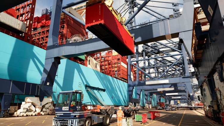 Crane lowering cargo container onto truck at Port of Felixstowe, England