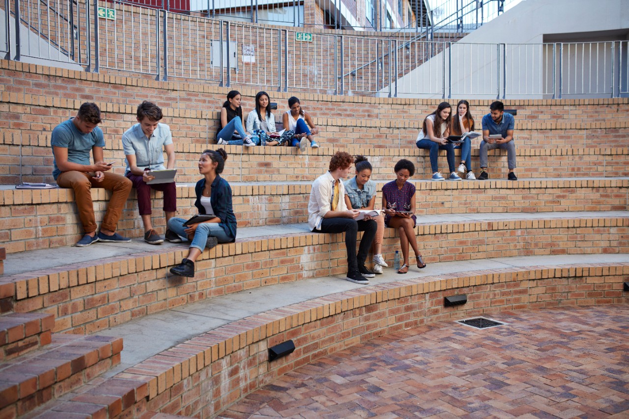Students studying in groups, in auditorium outside
